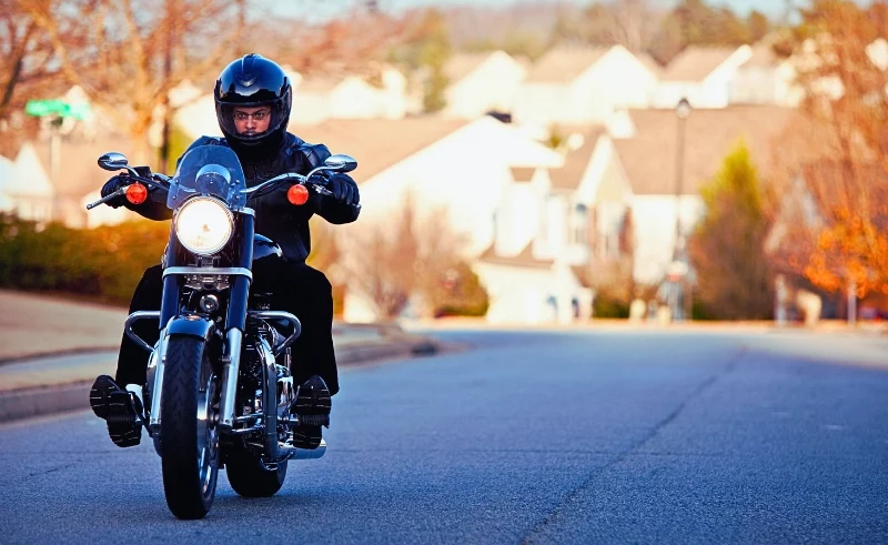 A man wearing a black jacket on his motorcycle.
